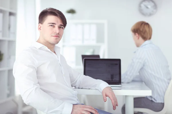 Porträtt av en ung man som sitter vid sitt skrivbord på kontoret — Stockfoto