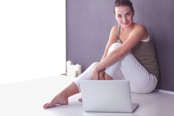 Holding laptop gülümseyen aşağı oturan genç casual kadın — Stok fotoğraf