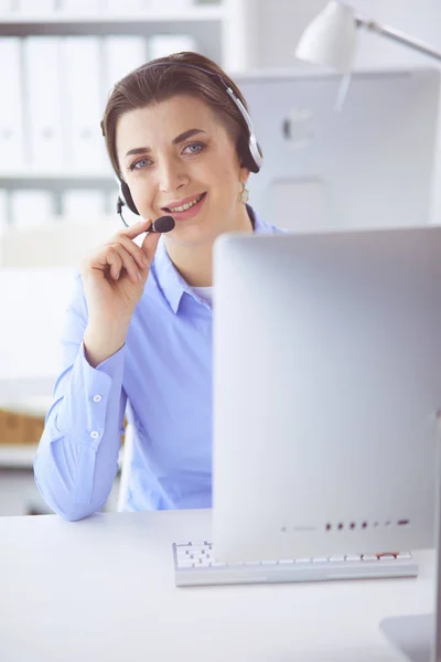 Ernstige mooie jonge vrouw die werkt als support telefoon operator met headset in het kantoor — Stockfoto