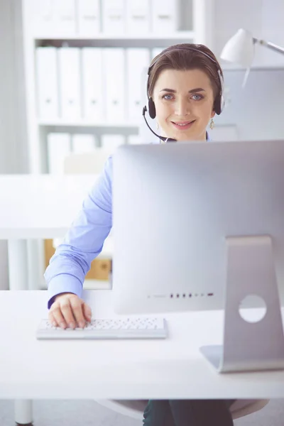 Mujer bastante joven y seria que trabaja como operador de telefonía de apoyo con auriculares en la oficina — Foto de Stock