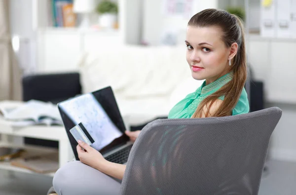 Hermosa joven morena en casa sentada en un sofá o sofá usando su computadora portátil —  Fotos de Stock