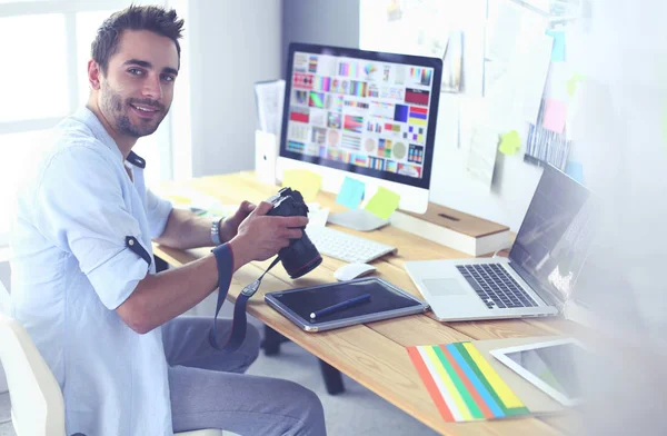 Portrait de jeune designer assis dans un studio graphique devant un ordinateur portable et un ordinateur tout en travaillant en ligne. — Photo