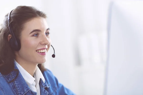 Retrato de mulher de negócios bonita trabalhando em sua mesa com fone de ouvido e laptop — Fotografia de Stock