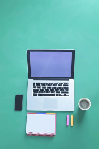 Mesa de escritório com laptop, telefone inteligente, xícara de café e suprimentos, isolado em fundo verde, flat lay — Fotografia de Stock