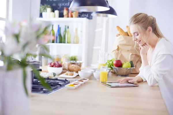 Красивая молодая женщина с помощью цифрового стола на кухне — стоковое фото
