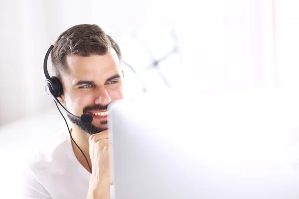 Ritratto di un giovane con un auricolare davanti a un computer portatile — Foto Stock