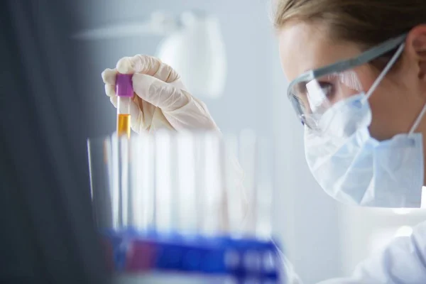 Un investigador médico o científico o un médico que observa un tubo de ensayo de solución verde líquida en un laboratorio — Foto de Stock