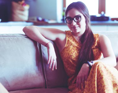 Kanepede oturan gülümseyen kadın portresi. Günlük tarz kapalı çekim.