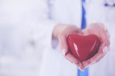 Steteskop tutan, kalbi hafif arka planda olan kadın bir doktor.