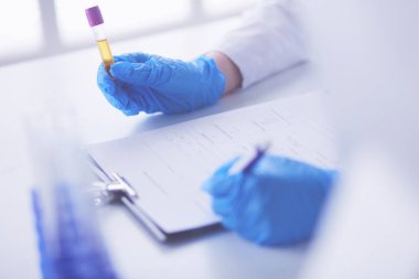 Kadın araştırmacı, beyaz arka planda izole edilmiş ilaç şişeleri ve mataralarla çevrili.