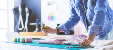 Moda tasarımcısı kadın stüdyoda tasarımları üzerinde çalışıyor.