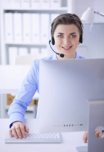 Ernstige mooie jonge vrouw die werkt als support telefoon operator met headset in het kantoor — Stockfoto