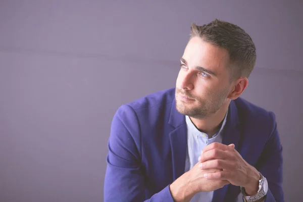 Young businessman sitting isolated on grey background. — Stock Photo, Image