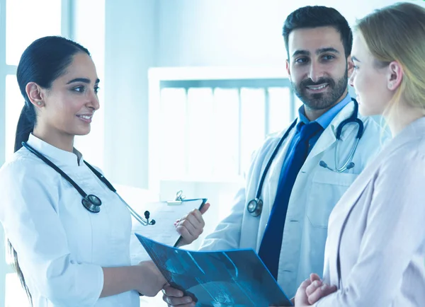 Médico bonito está conversando com jovem paciente do sexo feminino e fazendo anotações enquanto está sentado em seu escritório — Fotografia de Stock