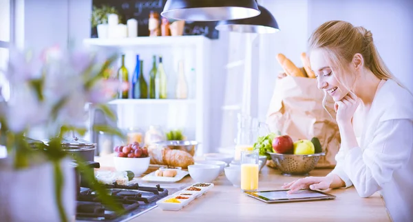 Hermosa joven usando una tableta digital en la cocina —  Fotos de Stock