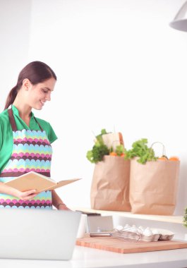 Genç kadın okuma kitabı evde mutfak gülümseyen