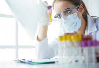 Modern laboratuvar veya hastanede plastik tıbbi tüplerle çalışan araştırmacı, doktor, bilim adamı veya laboratuvar asistanı.