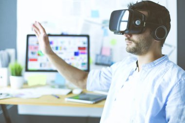 Genç erkek yazılım programcısı ofiste üç boyutlu sanal gerçeklik gözlükleriyle yeni bir uygulama test ediyor..