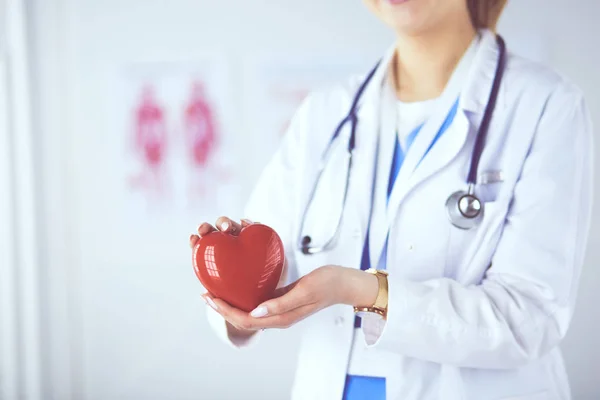 Medico femminile con stetoscopio che tiene il cuore, su sfondo chiaro — Foto Stock