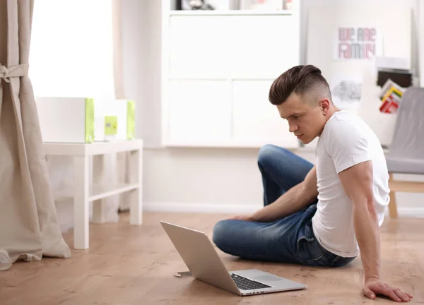 Yakışıklı olan bir dizüstü bilgisayar üzerinde çalışan ve yere oturmak — Stok fotoğraf