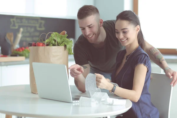 Koppel het betalen van hun rekeningen met laptop in de keuken thuis — Stockfoto