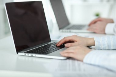 İş kadını ofis masasında oturuyor ve dizüstü bilgisayar elleriyle yazıyor