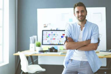 Dizüstü bilgisayar ve bilgisayar çalışırken önünde genç tasarımcı portresi. Onun mobil arka plan kullanarak Yardımcısı.