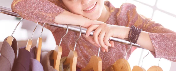 Mooie jonge stylist bij rek met hangers — Stockfoto