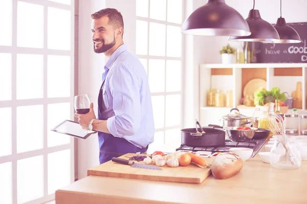 Man following recipe on digital tablet and cooking tasty and healthy food in kitchen at home