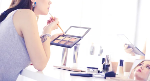 Mujer morena aplicando maquillaje para una cita nocturna frente a un espejo —  Fotos de Stock