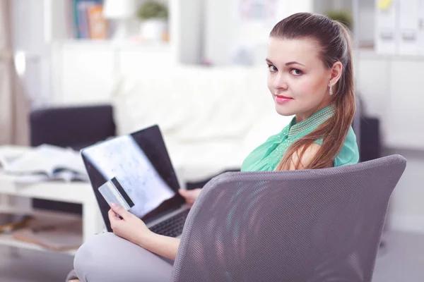 Hermosa joven morena en casa sentada en un sofá o sofá usando su computadora portátil — Foto de Stock