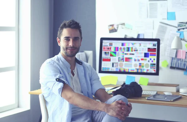 Porträt eines jungen Designers, der im Grafikstudio vor Laptop und Computer sitzt, während er online arbeitet. — Stockfoto