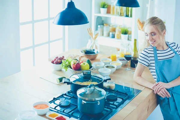 Mujer joven de pie cerca de escritorio en la cocina — Foto de Stock