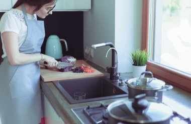 Masanın yanında duran mutfakta sebze doğrayan genç bir kadın..