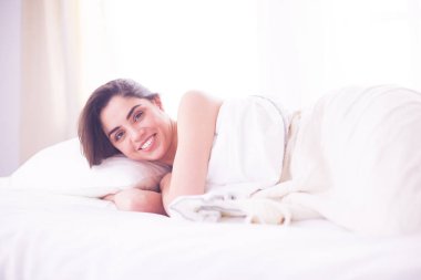 Güzel bir kadın yatağında uzanıyor.