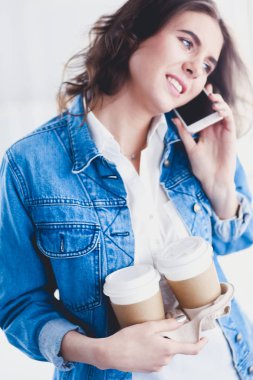 Genç iş kadını kafede telefonla konuşuyor.