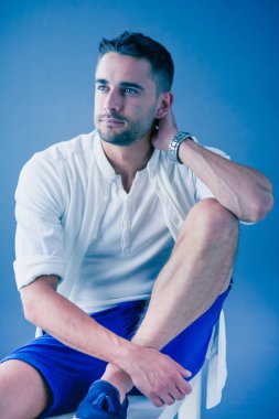 Gri arka planda yalnız oturan genç iş adamı.