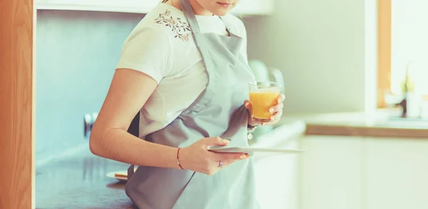 Ung kvinna med apelsinjuice och tablett i köket — Stockfoto