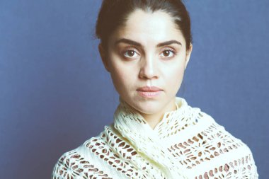 Bej örgü eşarp takan bir kadın.