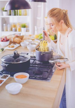 Evdeki mutfakta yemek pişiren güzel genç bir kadın.