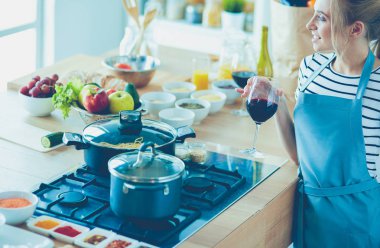 Güzel kadın mutfakta şarap içiyor.