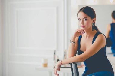 Beyaz arka planda izole edilmiş bir sandalyede oturan genç kadın.