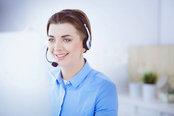 Ernstige mooie jonge vrouw die werkt als support telefoon operator met headset in het kantoor — Stockfoto