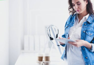 Gülümseyen kadın kahve içiyor ve kafede tablet kullanıyor.