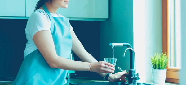 Woman filling a glass of water from a stainless steel or chrome tap or faucet — Stock Photo, Image