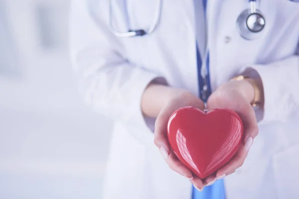 Medico femminile con stetoscopio che tiene il cuore, su sfondo chiaro — Foto Stock