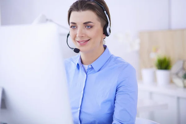 Mujer bastante joven y seria que trabaja como operador de telefonía de apoyo con auriculares en la oficina — Foto de Stock