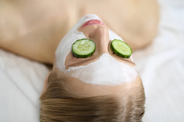 Belle jeune femme recevant un masque facial de concombre dans un salon de beauté — Photo