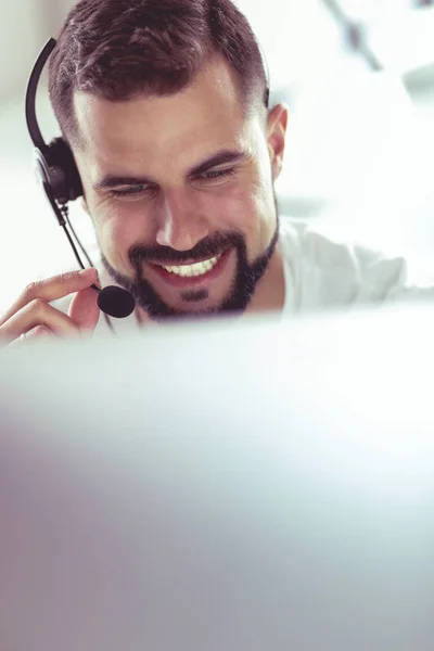 Porträtt av en ung man med ett headset framför en bärbar dator — Stockfoto