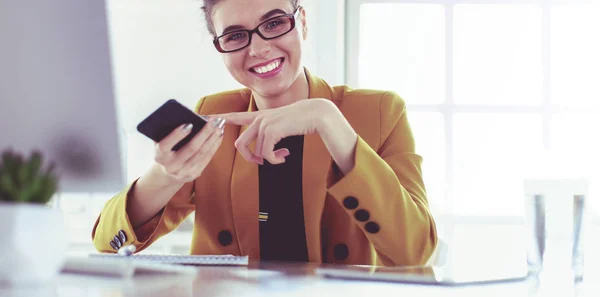 Businesswoman sitting in office with laptop on telephone — Stock Photo, Image